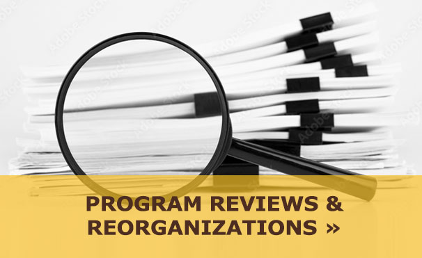 Maginfying glass over papers with text: Program Reviews & Reorganizations