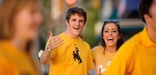 Two students in yellow shirts smile at the camera.