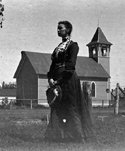 Gray in a dress standing in front of a school building
