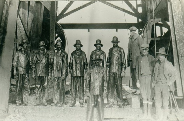 Oil workers covered in crude oil