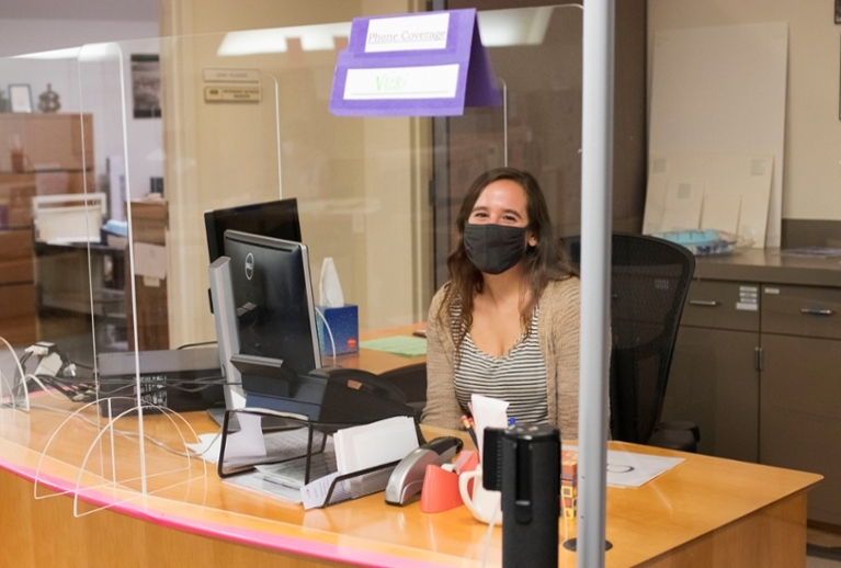 Reference Desk attended by Archivist wearing a mask.