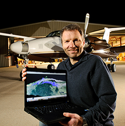 Scientist with laptop in front of research aircraft