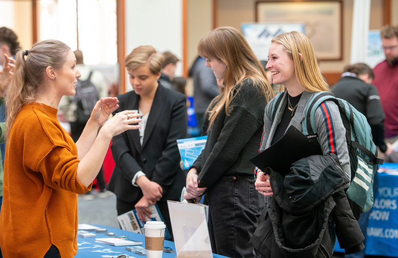Student chat with employers at a career fair booth 