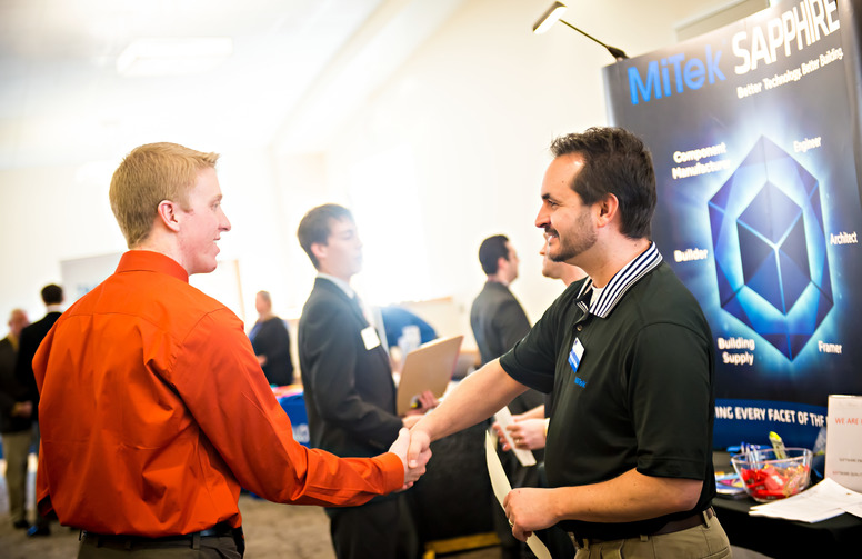 student shakes hands with a business representative at a job fair