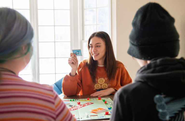 A diverse group of students playing a Monopoly board game