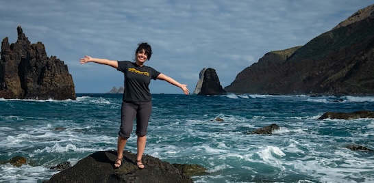 student posing on rocks in front of ocean