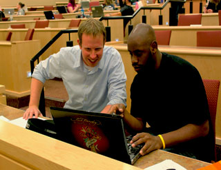 Two College of Law students working together on a laptop.
