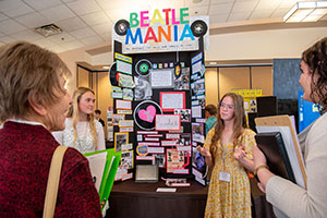 Two young women explaining exhibit to onlookers