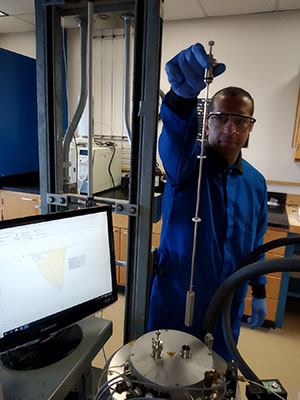 photo of man holding a metal device in a lab