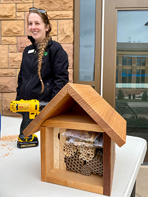 woman with small wooden bee house, similar to a bird house