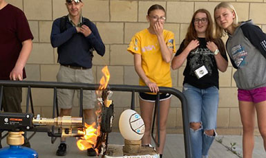people looking on as a flame blasts an egg