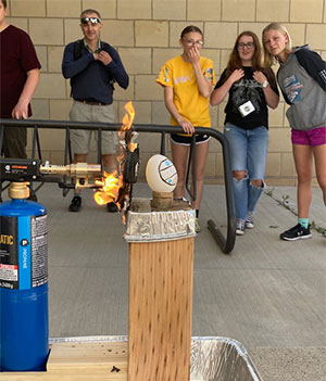 people looking on as a flame is blasting towards an egg