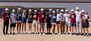row of people in hard hats posing in front of building