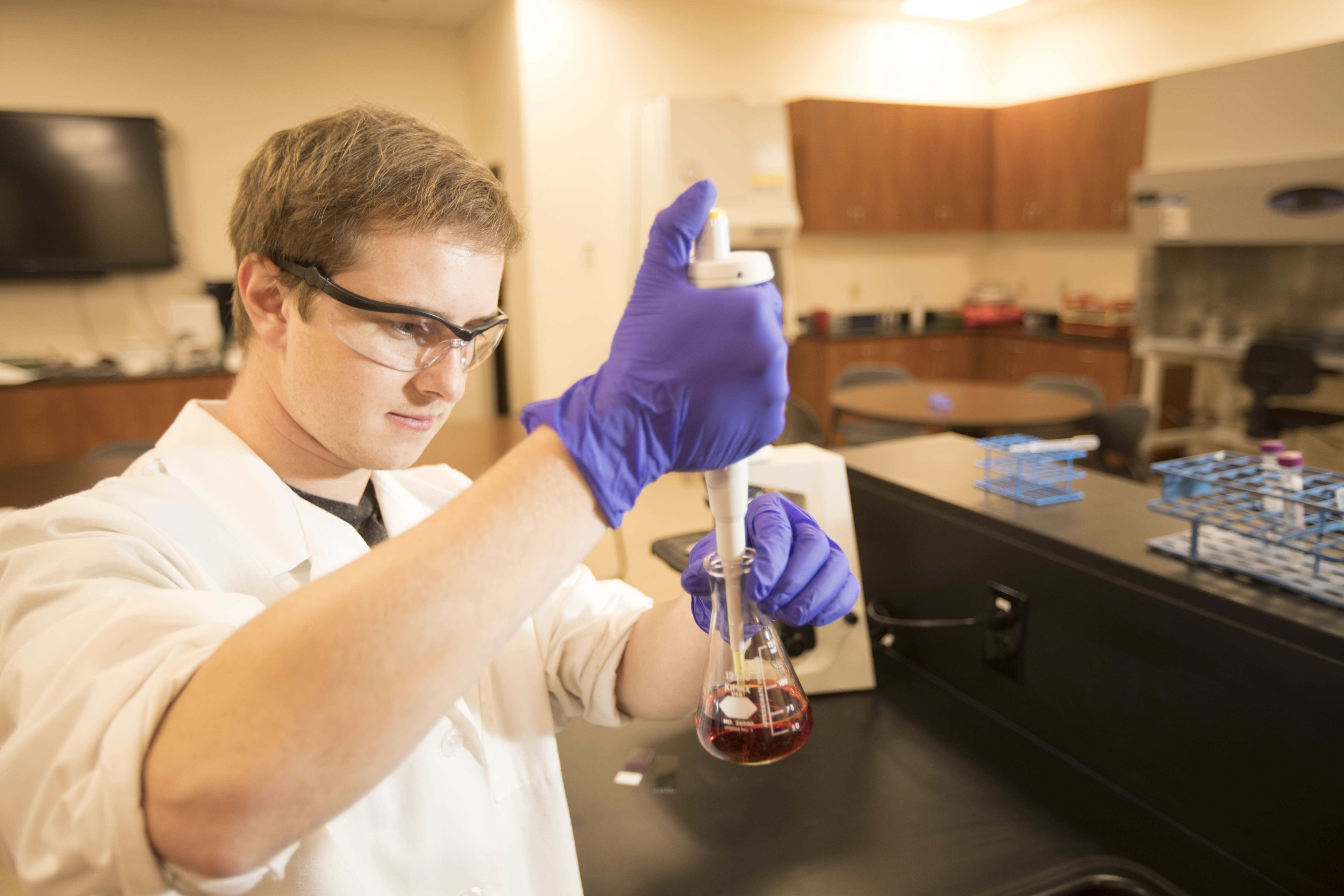 Male student examining liquid in a laboratory. 