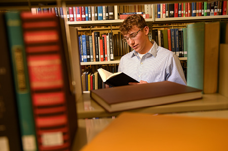 A student reads a book in a stack inside the Coe Library.