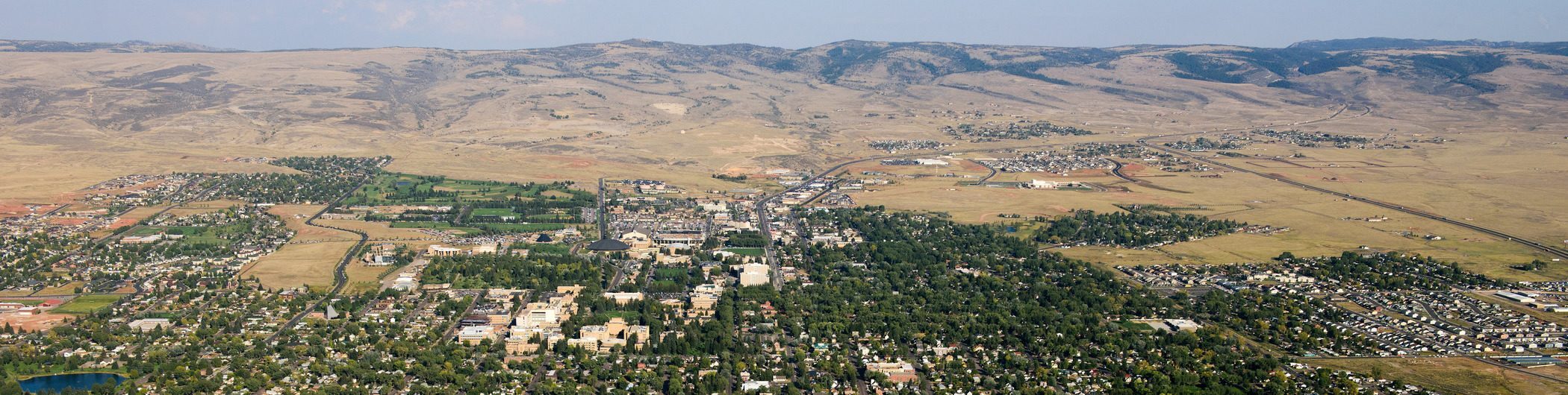 an aerial view of the city of Laramie with houses in the foreground and the plains and mountains in the distance