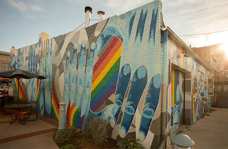 a colorful mural with rainbows and hands on a building in downtown Laramie