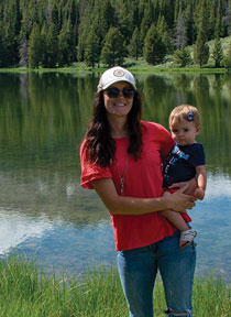 woman standing in front of a lake while holding a small child