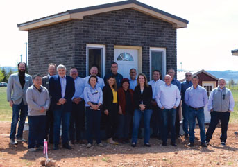 group of people standing in front of a tiny brick building